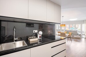 A modern kitchen with a stainless steel sink, a coffee machine, and a black countertop.