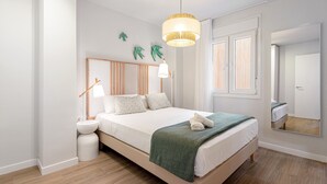 A bedroom with a bed, bedside table, lamp, and a mirror.