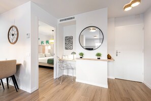 A modern interior with a wooden floor, a clear desk, a chair, a round mirror, and a door. - Holiday Apartment "Floperw 1" with Wi-Fi (Malaga)