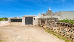 A building with a stone wall, a black door, and a clear blue sky. - Villa "Trulli Cinque Nicchie" with Private Terrace & Wi-Fi (Martina Franca)