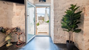 A hallway with a rustic stone wall, a potted plant, a hookah, and a door leading to an outdoor area with a white umbrella. - Villa "Trulli Cinque Nicchie" with Private Terrace & Wi-Fi (Martina Franca)