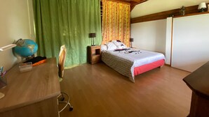 Una habitación con cama, escritorio, silla, un globo terráqueo, cortinas y un armario.