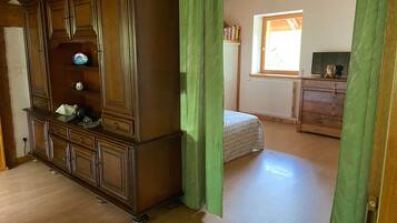 A room with a large wooden cabinet, a bed, a dresser, and a window with natural light.