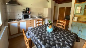 Cocina compacta con estufa a gas, microondas y armarios blancos.