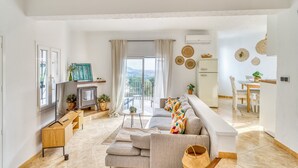 Un salon moderne avec un canapé, une télévision et un balcon offrant une vue agréable.