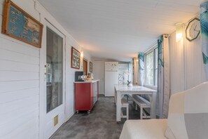 Une cuisine compacte comprenant un réfrigérateur, une petite table à manger et un banc.
