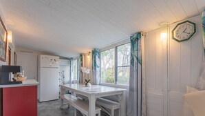 Een keuken met een witte tafel en een bank, een rode kast en een klok aan de muur.