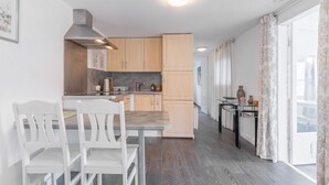 Een moderne keuken met houten kastjes, een roestvrijstalen afzuigkap en een eethoek met witte stoelen.