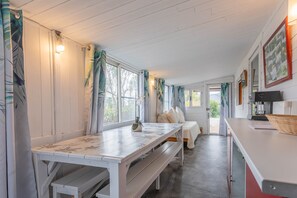 Une pièce chaleureuse avec un banc en bois blanc, un lit avec des oreillers, une table avec une lampe et un cadre photo fixé au mur.