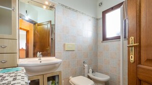 A bathroom with a sink, toilet, bidet, and a mirror.