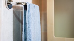 A bathroom with a towel rack, a bathtub, and a tiled wall.