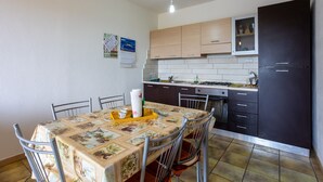 A kitchen with a dining table, chairs, cabinets, and a stove.