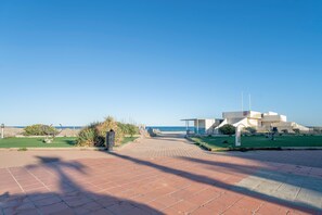 A paved pathway leading to a building with a clear view of the sea.