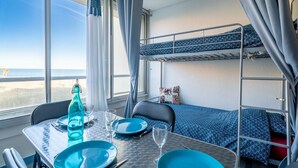 Camera con letto a castello, un tavolo imbandito per due, una bottiglia e vista sul mare.