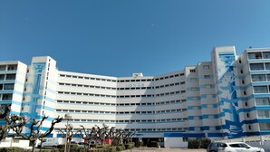 Un edificio a più piani con facciata curva, un segno ben visibile 'JONES' e un'area di parcheggio con veicoli.