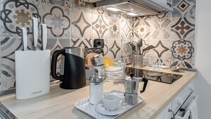 Una cucina con una macchina da caffè, un bollitore, un macinino per caffè e un vassoio con tazza e piattino.