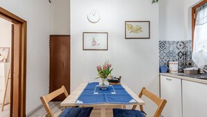 Zona pranzo con tavolo in legno, tovaglia blu e due sedie di legno con cuscini blu.