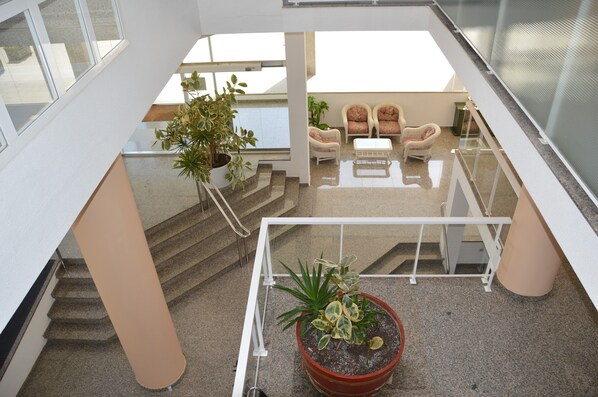 A modern interior with a staircase, seating area, and potted plants.