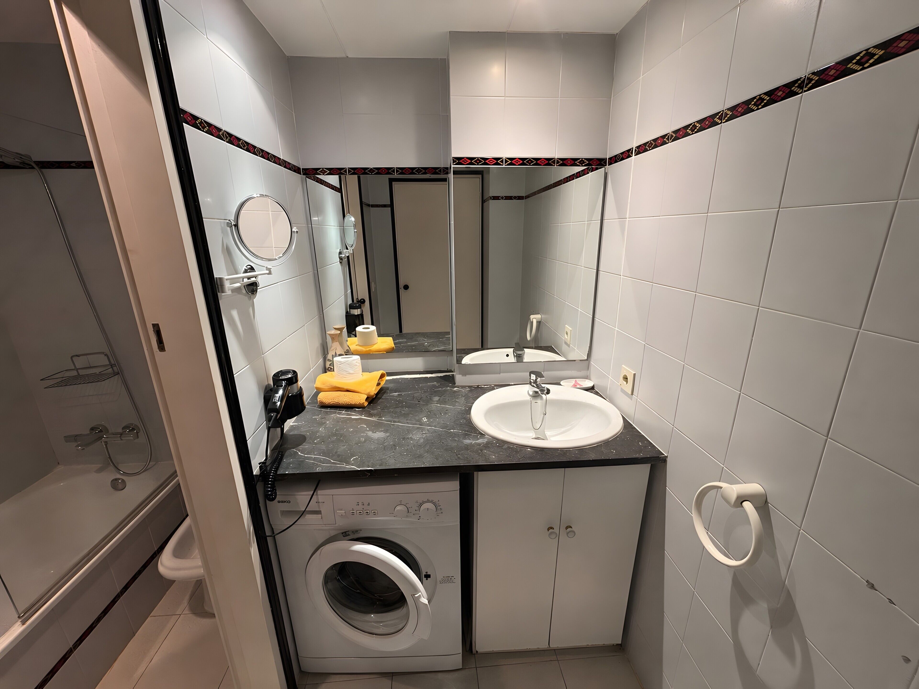 Un baño pequeño con lavadora, dos lavamanos, un espejo y ducha.