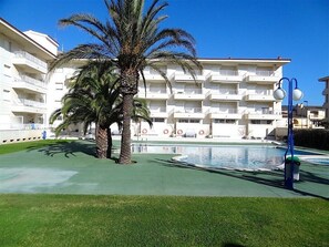 Ein Hotel mit Pool, Palmen und einem mehrstöckigen Gebäude mit Balkonen.
