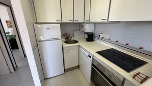 A kitchen with white cabinets, a refrigerator, a microwave, a coffee maker, and a stove. - Apartment 'Blaumar B310' with Shared Pool, Private Terrace and Wi-Fi (LÈstartit)