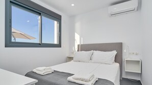 A modern hotel room with a bed, bedside tables, an air conditioning unit, and a window with a view. - Holiday Home 'Villa Infinite' with Sea View, Wi-Fi and Air Conditioning (Salobreña)