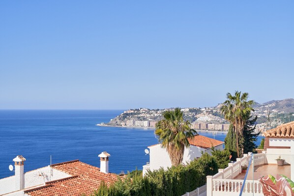 A coastal view with a clear blue sky, a white building with a red-tiled roof, and a palm tree. - Holiday Home 'Villa Infinite' with Sea View, Wi-Fi and Air Conditioning (Salobreña)