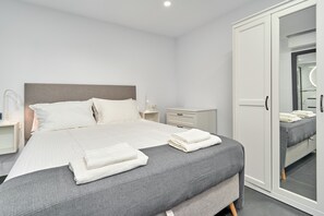 Ett modernt hotellrum med en stor säng, en garderob, ett sängbord och en spegel.
