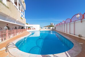 A swimming pool with a red railing, a clear blue sky, and a building with balconies. - Duplex Apartment in Montechoro with Shared Pool, Wi-Fi & Air Conditioning (ALBUFEIRA)