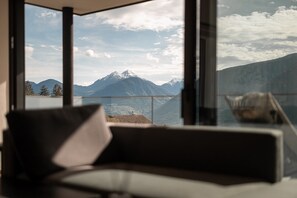 Une pièce dotée d’une grande fenêtre donnant sur les montagnes, d’un canapé et d’une petite table.
