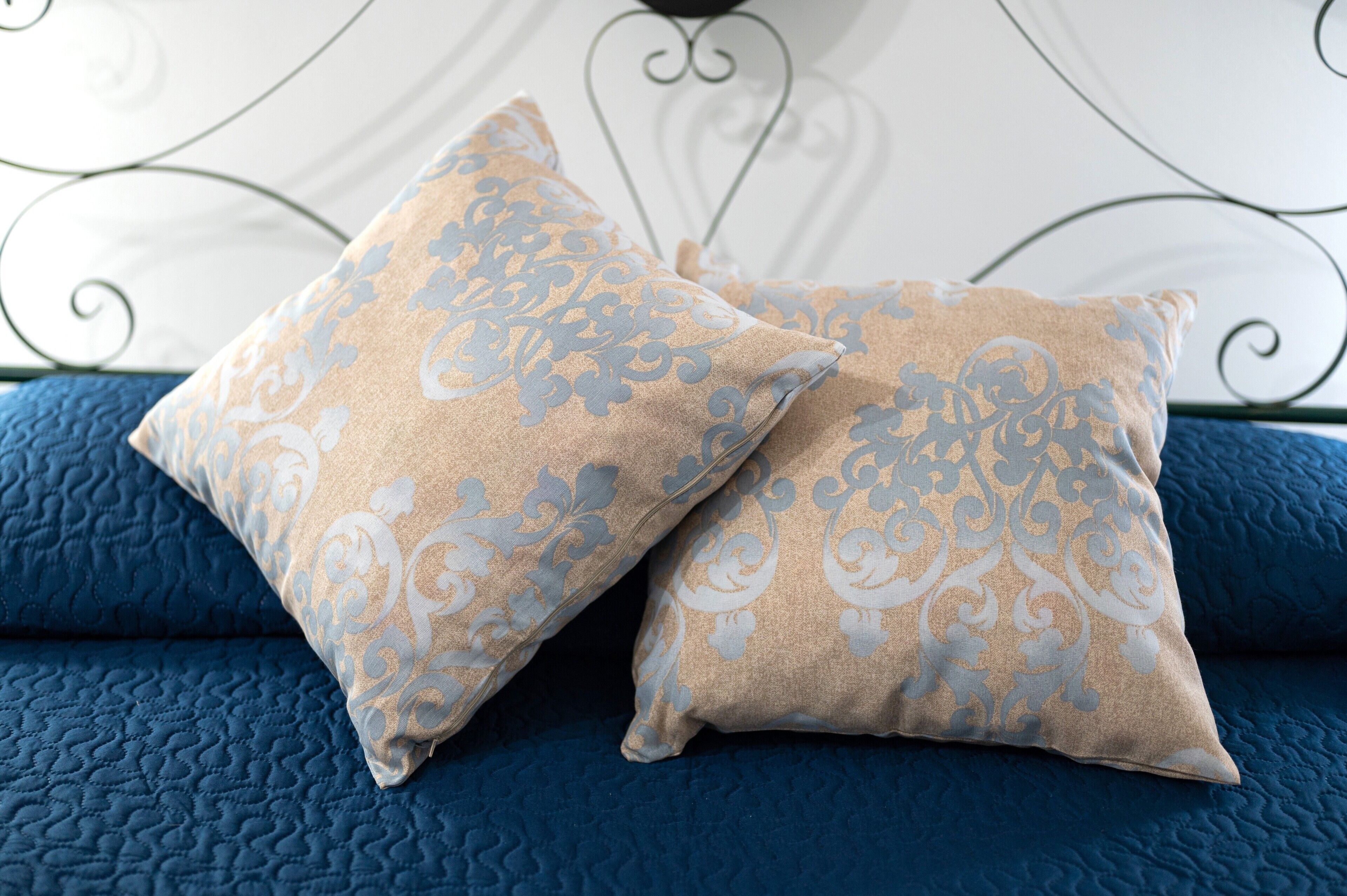 Dos almohadas con estampado floral sobre una colcha azul.