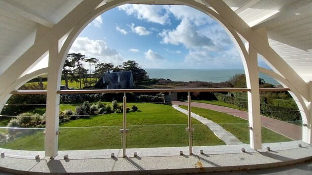 Un espacio al aire libre techado con vistas al mar y un paisaje con césped.