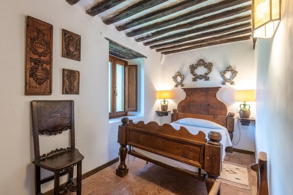 Une chambre à coucher de style traditionnel, avec un lit en bois, une chaise et des éléments de décoration fixés au mur.