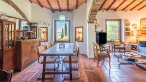 Ein rustikales Interieur mit einem Holzespeisetisch, Stühlen, einem Fernseher und einem Kamin.