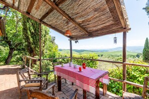 Una pérgola de madera con una mesa preparada para dos, con vistas a un paisaje exuberante.