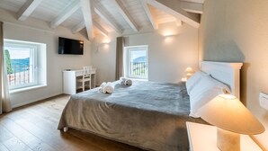 Ein Schlafzimmer mit einem Bett, einem Schreibtisch, einem Stuhl, einem Fernseher und einem Fenster mit Blick.