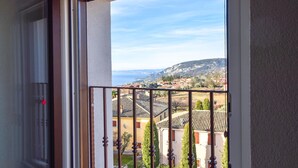 Ein Balkon mit Metallgeländer, der auf einen Wohnbereich mit Häusern und einem entfernten Gebirge blickt.