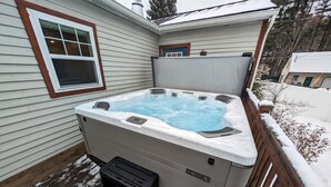 Ein Whirlpool mit Bedienfeld, Stufen und einer Holzterrasse.