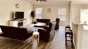 A modern living room with a flat-screen TV, a ceiling fan, and a dining area with a table and chairs. - Like New Home close to town family friendly, quiet and close to amenities.  (Conway)