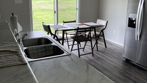 A modern kitchen with a marble countertop, a stainless steel refrigerator, and a dining table with chairs. - Like New Home close to town family friendly, quiet and close to amenities.  (Conway)