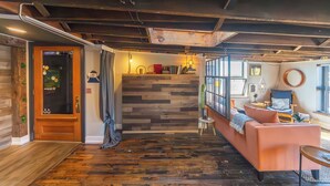 A cozy room with a wooden floor, a sofa, a small table, and a window with a view.