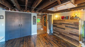 A room with a wooden ceiling, a sliding door, a wooden wall, and a bookshelf.