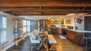 A rustic kitchen with wooden beams, a dining area with a bench, and a bar area.