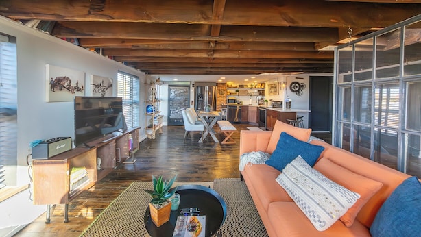 A spacious living area with a wooden ceiling, a sofa, a coffee table, and a television.
