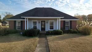 A single-story house with a dark roof, white trim, and a front porch.