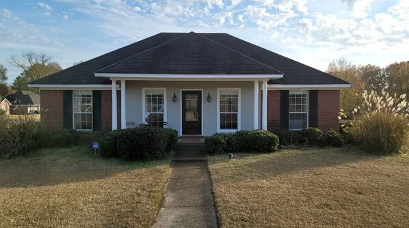 A single-story house with a dark roof, white trim, and a front porch.