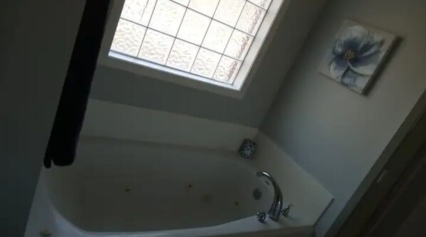 A bathroom with a bathtub, a window, and a wall-mounted artwork. - Fully furnished home, sleeps 8 (Terry)