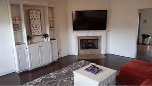 A living room with a fireplace, a flat-screen TV mounted above it, and a red couch.