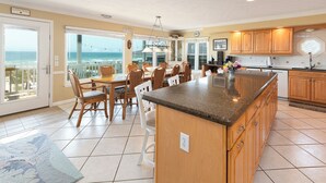 A spacious kitchen with a large island, wooden cabinets, and a view of the ocean. - Hobbs Realty - Enjoy "Southern Comfort" at it's best in this gorgeous oceanfront home! (Holden Beach)