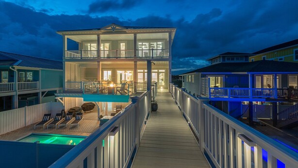 A two-story waterfront property with a covered deck, a pool, and multiple balconies.